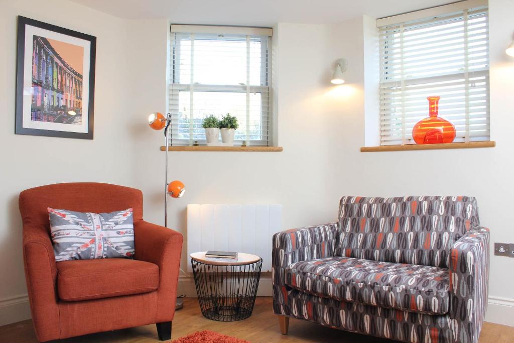 a living room with a arm chair and a chair and a chair at Bath View Apartments in Bath