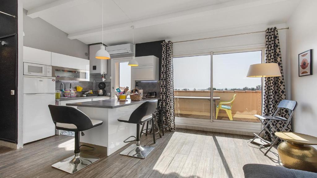 - une cuisine avec un comptoir et des chaises dans la chambre dans l'établissement Neptuna- 217L- Appart charme- 6 pers, au Cap d'Agde