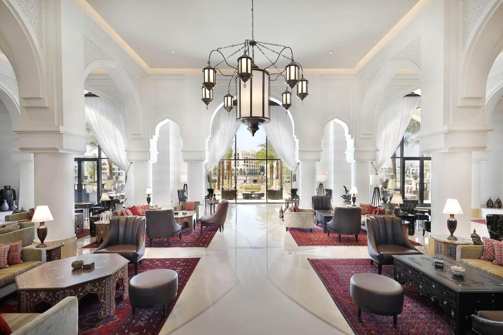 a lobby with chairs and tables and a chandelier at Al Manara, a Luxury Collection Hotel, Aqaba in Aqaba