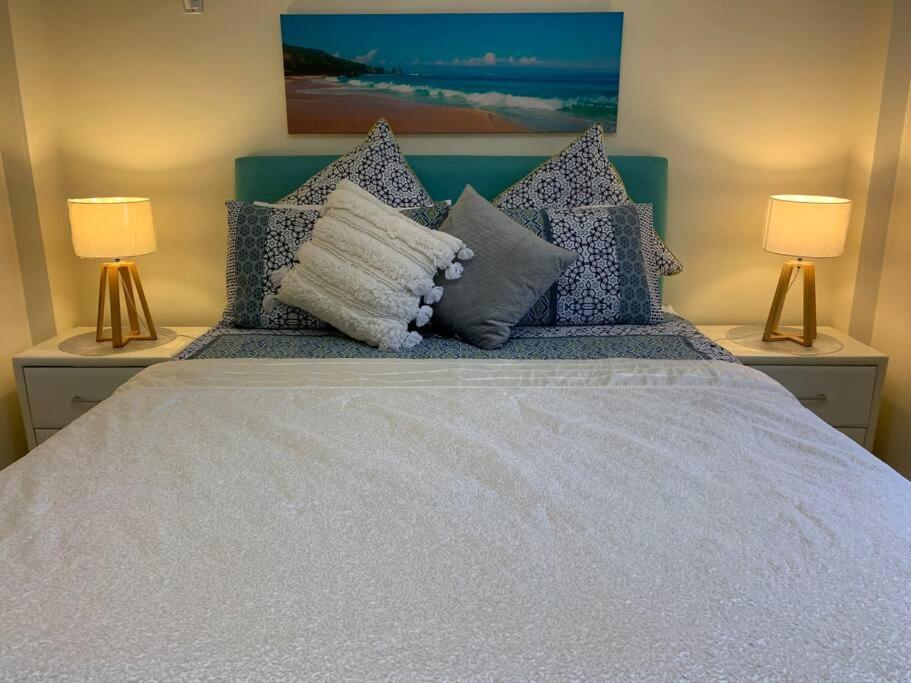 a bedroom with a bed with pillows and two lamps at Boutique Granny Flat in Paraparap