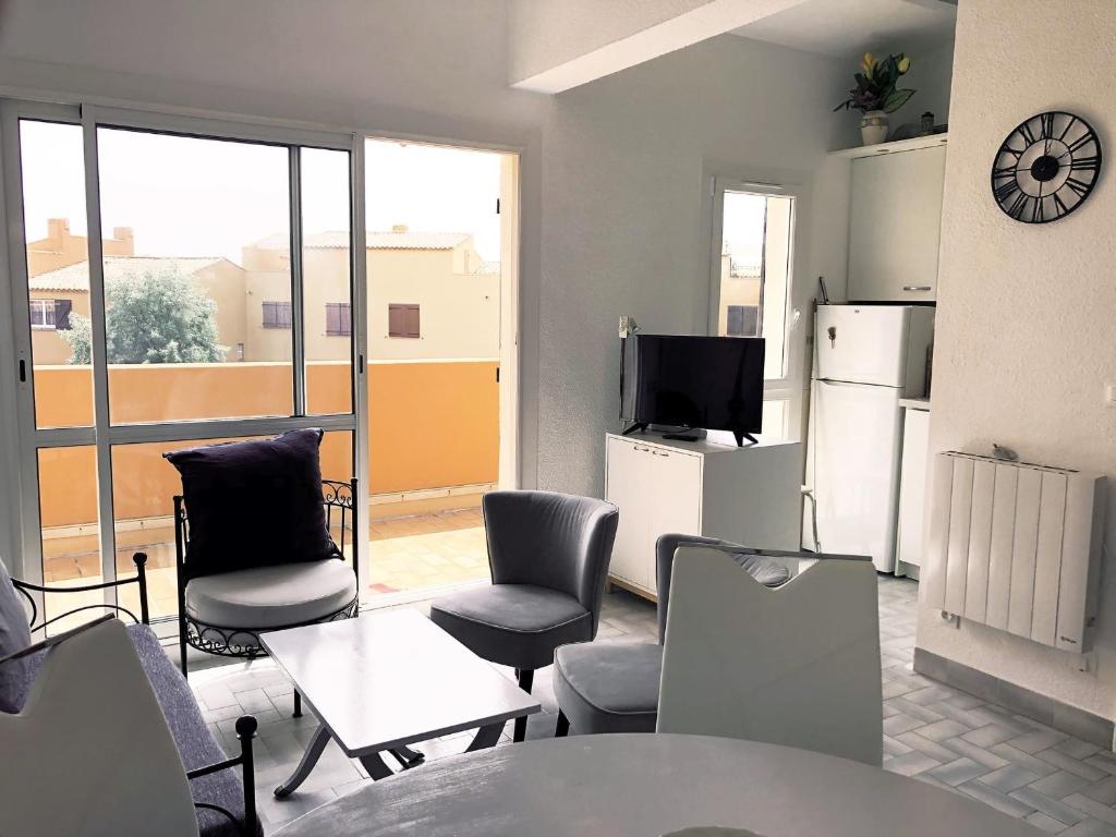 a living room with chairs and a table and a tv at Neptuna- 52B- Appart spacieux- 7 pers in Cap d'Agde