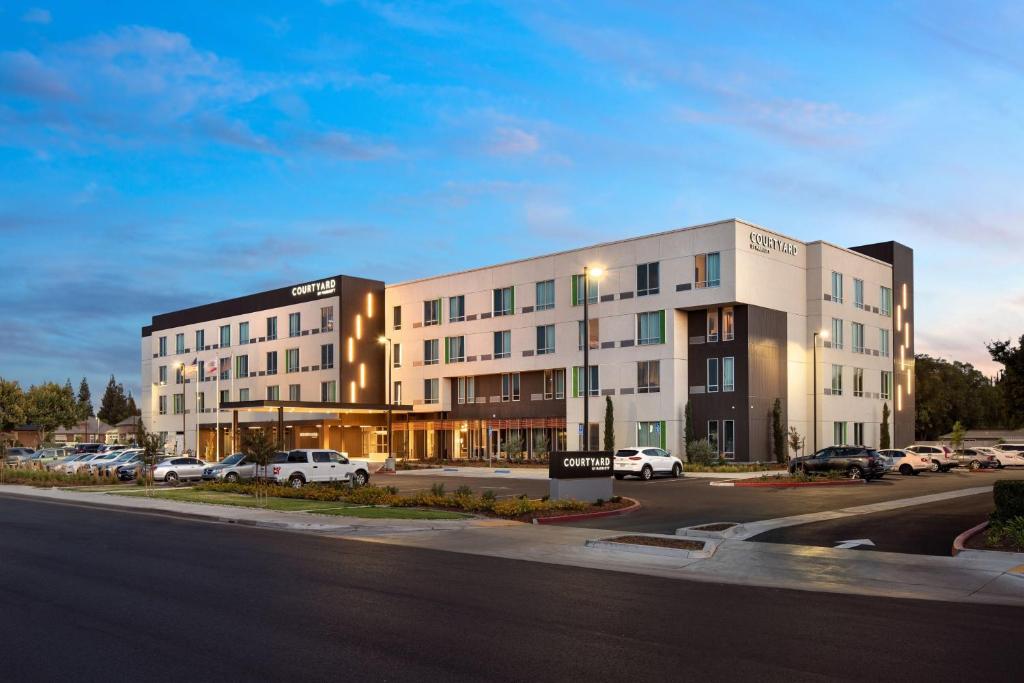 een groot gebouw met auto's geparkeerd op een parkeerplaats bij Courtyard by Marriott Fresno Clovis in Clovis