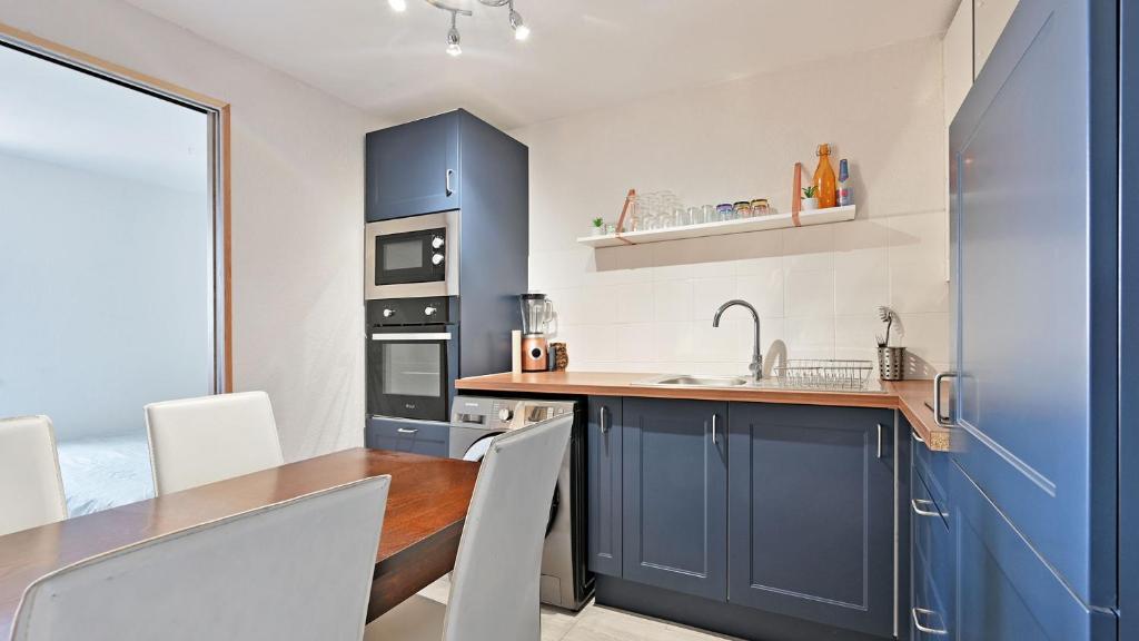 a kitchen with blue cabinets and a wooden table at Terrasses de la Plage- 257- Appart moderne- 4 pers in Cap d'Agde