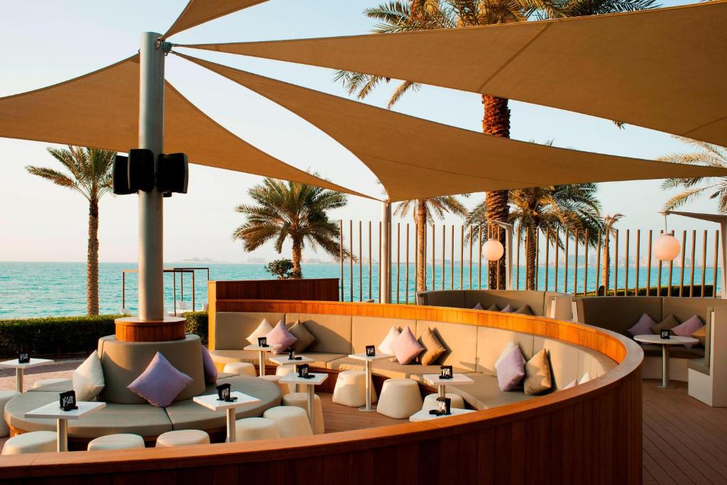 a restaurant with tables and umbrellas and the ocean at Sheraton Jumeirah Beach Resort in Dubai
