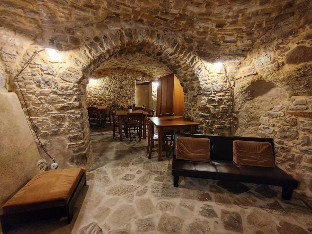 a dining room with a stone wall with tables and benches at Borgo Sciugolo in Baselice