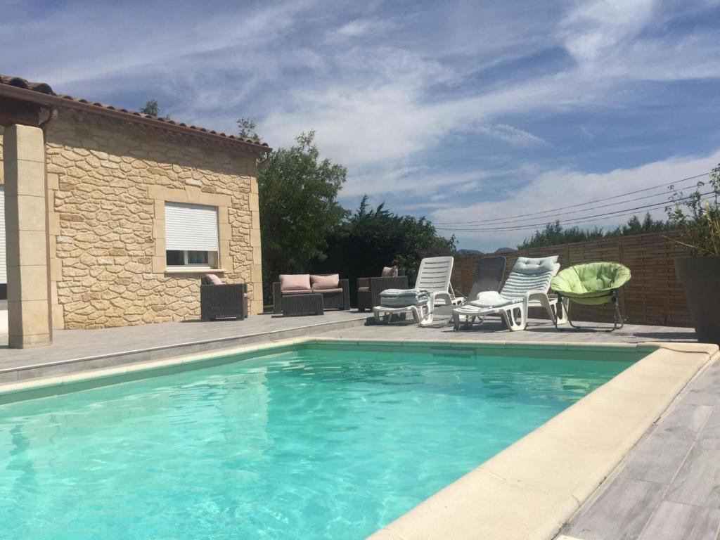 a swimming pool with two chairs and a house at Villa Emma 10 &#47; 12 personnes in Grignan
