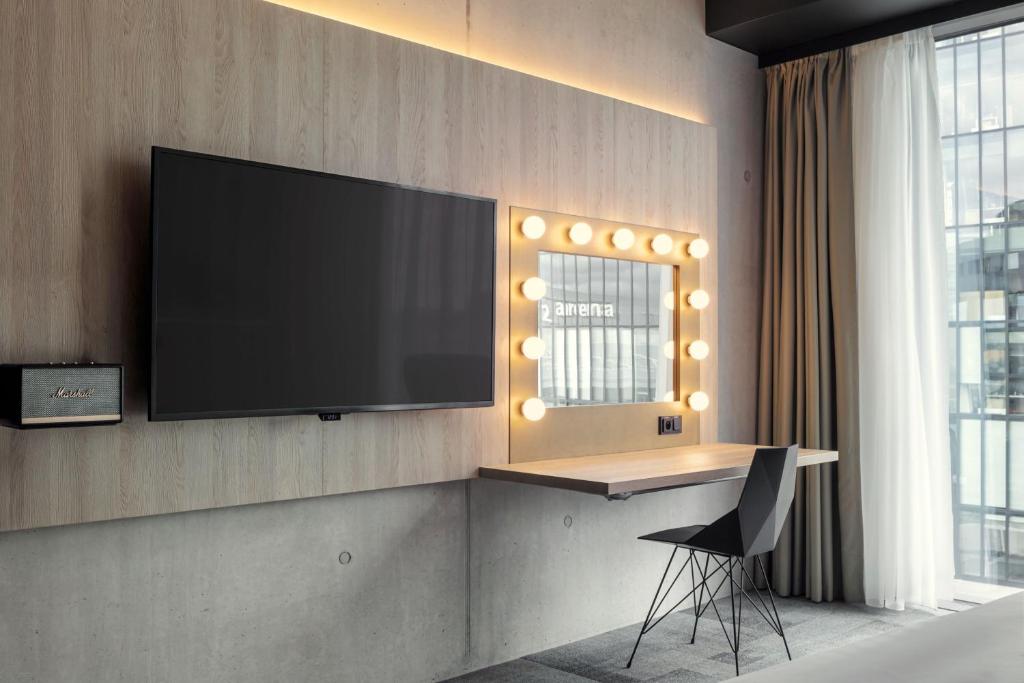 a tv on a wall with a desk and a chair at STAGES HOTEL Prague, a Tribute Portfolio Hotel in Prague