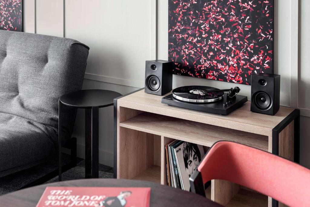 a living room with a chair and a table with speakers at STAGES HOTEL Prague, a Tribute Portfolio Hotel in Prague