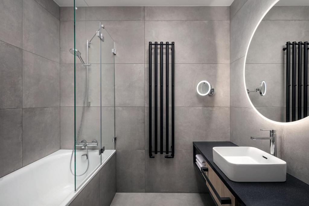 a bathroom with a tub and a sink and a mirror at STAGES HOTEL Prague, a Tribute Portfolio Hotel in Prague