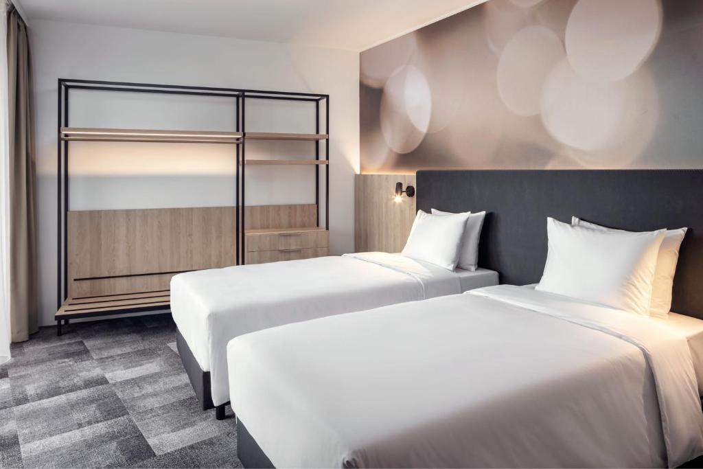 a hotel room with two beds and a mirror at STAGES HOTEL Prague, a Tribute Portfolio Hotel in Prague