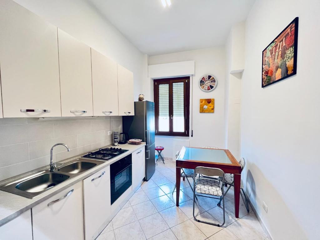 a kitchen with white cabinets and a table and a sink at Be Your Home - Casa Vacanze Il Posticino in Civitavecchia