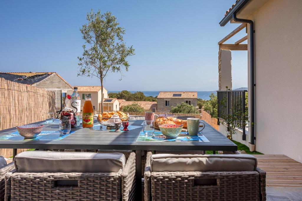 una mesa con comida en un balcón con sillas en Di Luce, en Lumio