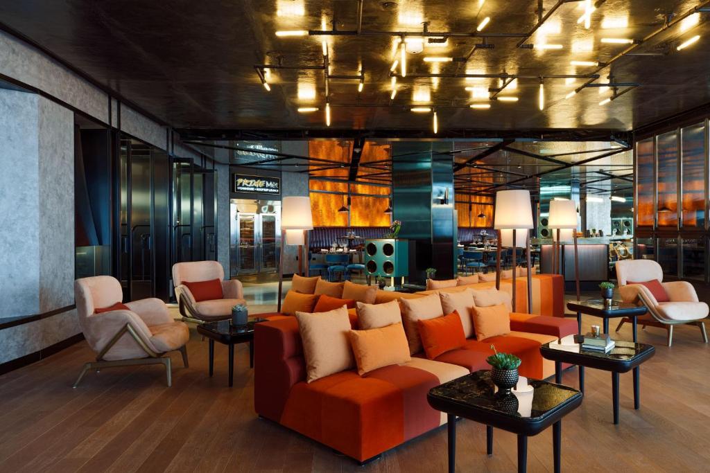 een lobby met een bank, stoelen en tafels bij Renaissance New York Flushing Hotel at Tangram in Queens