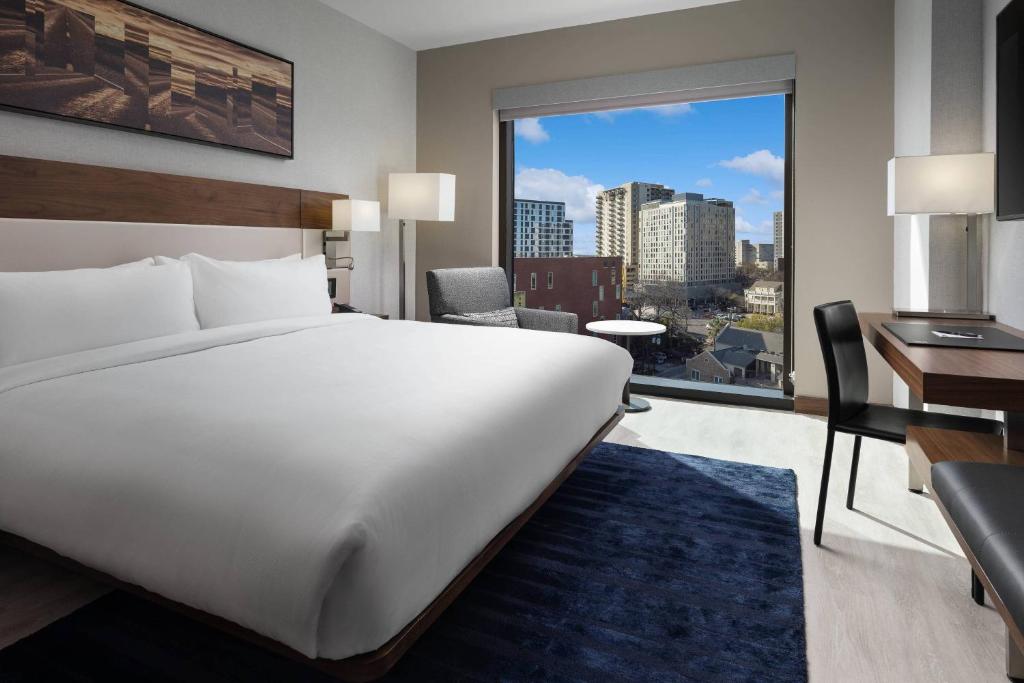 a bedroom with a large white bed and a large window at AC Hotel by Marriott Austin-University in Austin