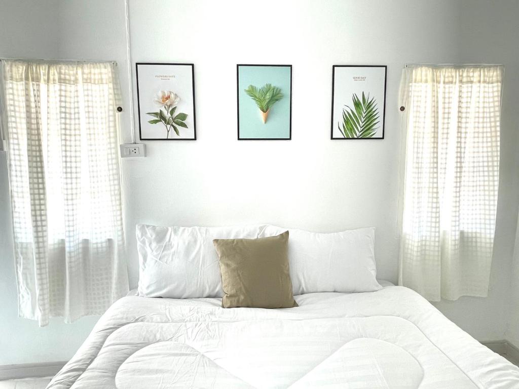 a bedroom with a white bed with four pictures on the wall at Seamsak hotel in Golden Triangle