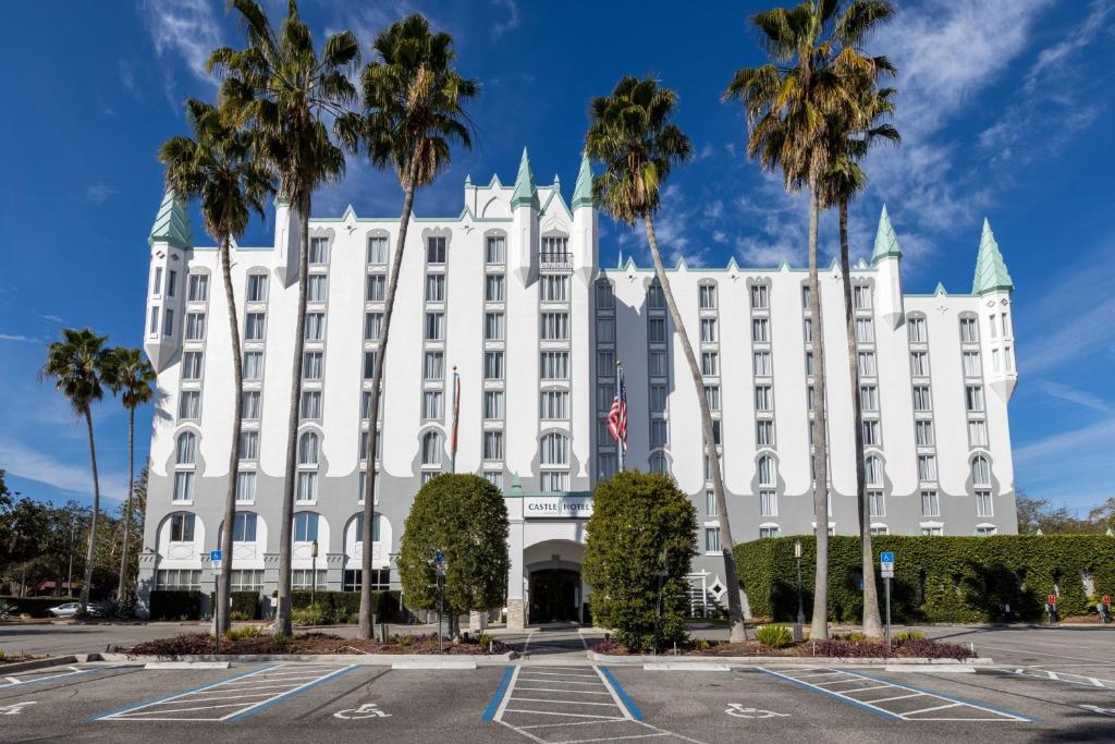 un bâtiment blanc avec des palmiers dans un parking dans l'établissement Castle Hotel, Autograph Collection, à Orlando