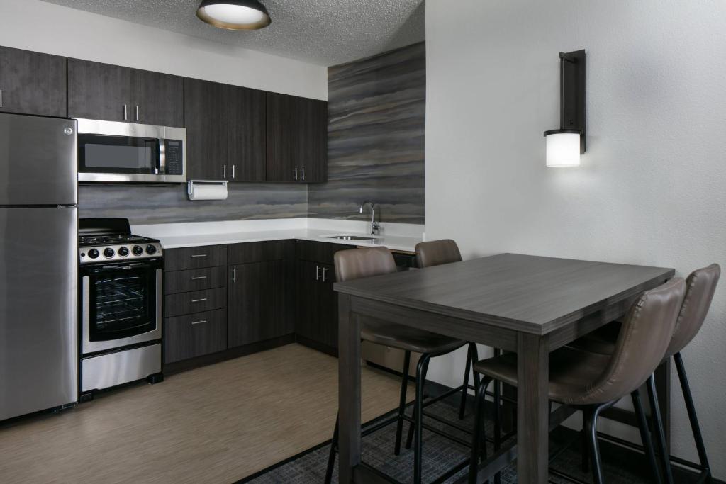 a kitchen with a table and a stove and refrigerator at Residence Inn by Marriott Tulsa South in Tulsa