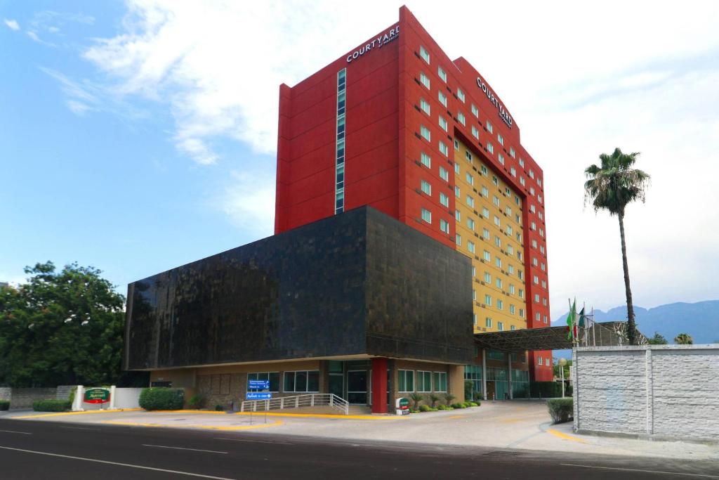 een rood en geel gebouw aan de straatkant bij Courtyard Monterrey San Jeronimo in Monterrey