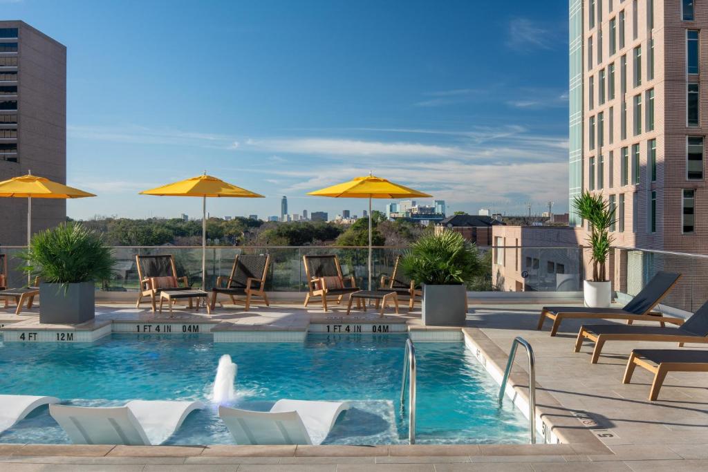 a pool on the roof of a building with chairs and umbrellas at The Westin Houston Medical Center - Museum District in Houston