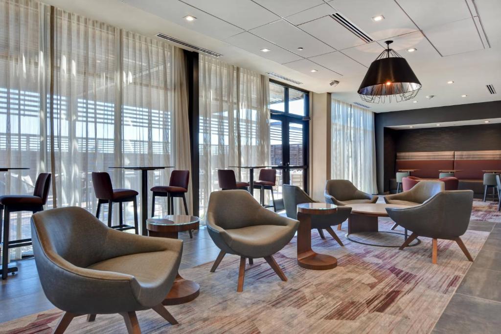 a waiting room with chairs and tables and windows at Courtyard by Marriott Bentonville Rogers Promenade in Rogers