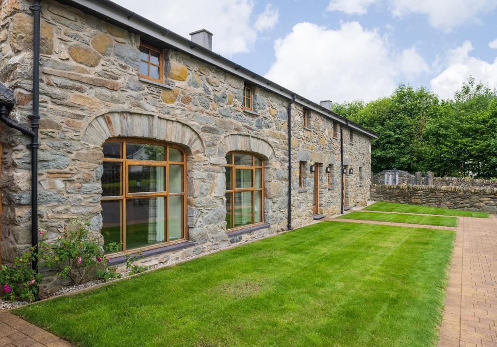 an old stone building with a lawn in front of it at Glandwr Cottage at Hendre Rhys Gethin in Betws-y-coed