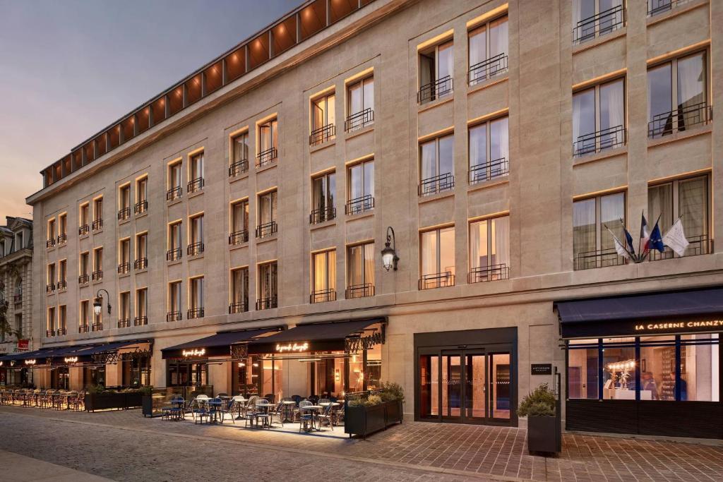 een groot gebouw met tafels en stoelen ervoor bij La Caserne Chanzy Hotel & Spa, Autograph Collection in Reims