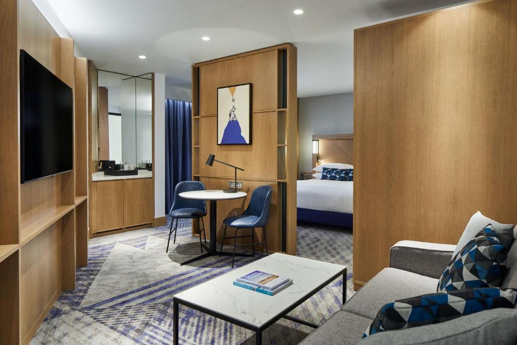 een hotelkamer met een kingsize bed en een woonkamer bij Courtyard by Marriott Exeter Sandy Park in Exeter