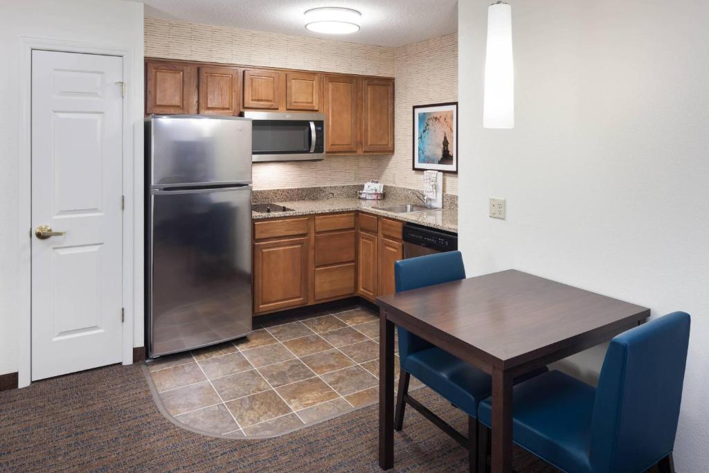 a kitchen with a table and a stainless steel refrigerator at Residence Inn Kansas City Country Club Plaza in Kansas City