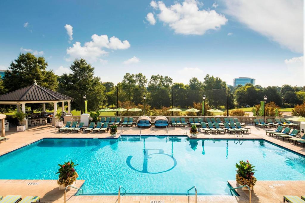 a large swimming pool with lounge chairs and tables at The Ballantyne, a Luxury Collection Hotel, Charlotte in Charlotte