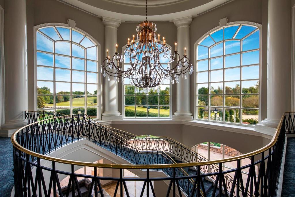 a large staircase with a chandelier in a room with windows at The Ballantyne, a Luxury Collection Hotel, Charlotte in Charlotte