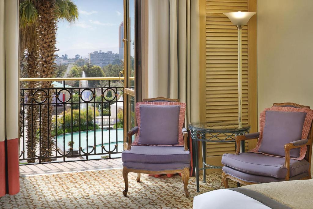 a room with two chairs and a balcony with a view at Sheraton Addis, a Luxury Collection Hotel, Addis Ababa in Addis Ababa