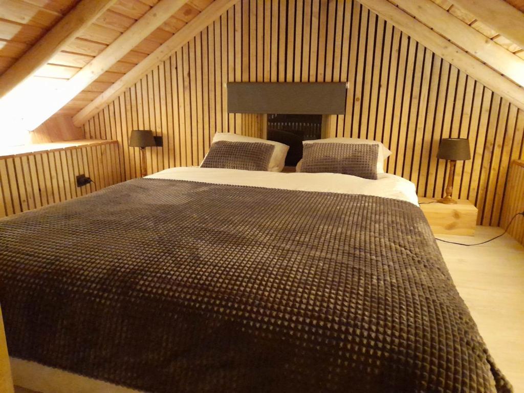een groot bed in een kamer met houten wanden bij Ô ptit Zébo in Bras