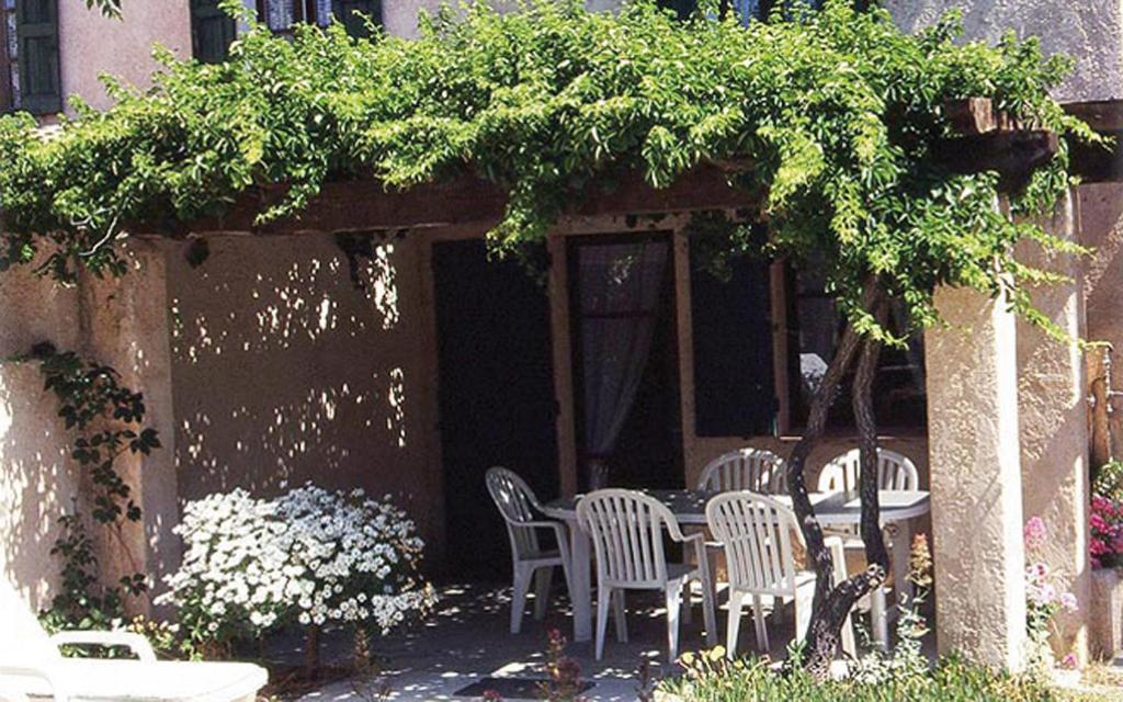 une terrasse avec des chaises et une table sous un parasol dans l'établissement Au jardin de la ferme - gite vigne vierge, à Six-Fours-les-Plages