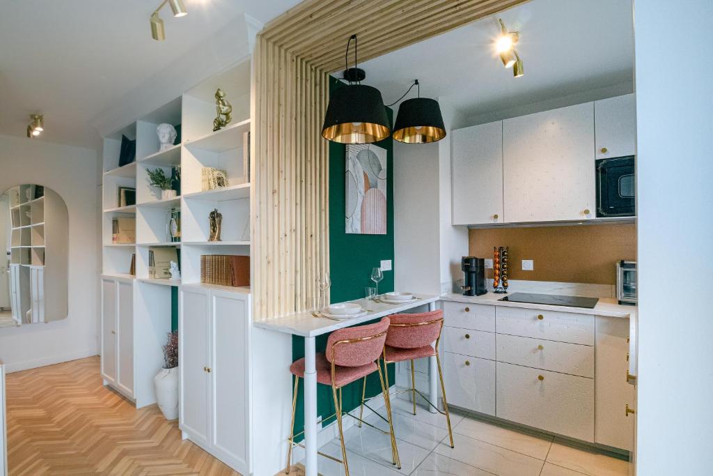 una cocina con armarios blancos y una barra con taburetes en The Green Home - Quiet and Fully Equipped High-End Studio with parking, en Courcouronnes