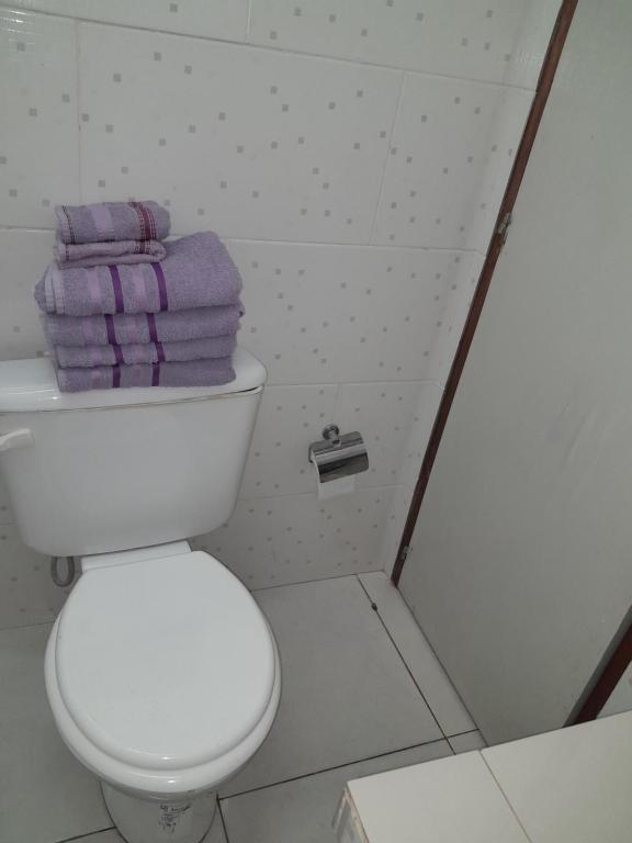 y baño con aseo blanco y toallas púrpuras. en FERISADU en Puerto Iguazú