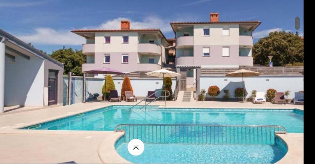 - une piscine en face d'une grande maison dans l'établissement Apartma DOLORES, à Vodnjan