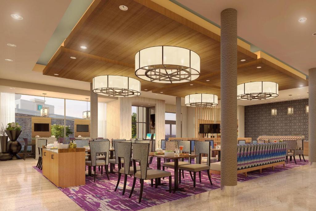 um restaurante com mesas, cadeiras e lustres em SpringHill Suites by Marriott Fayetteville Fort Liberty em Fayetteville