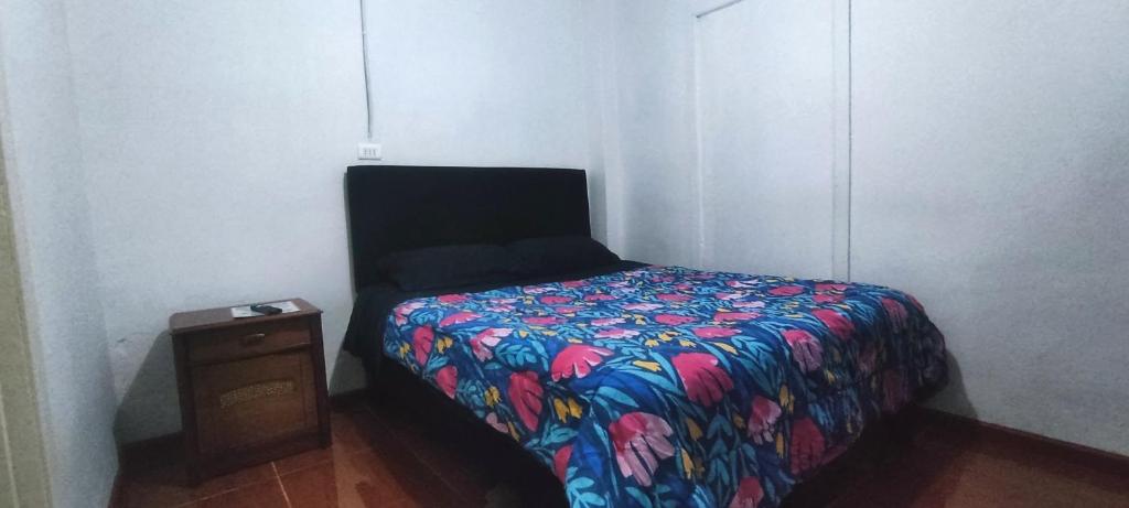 a bed with a colorful comforter in a room at Hospedaje curicó casa grande in Curicó