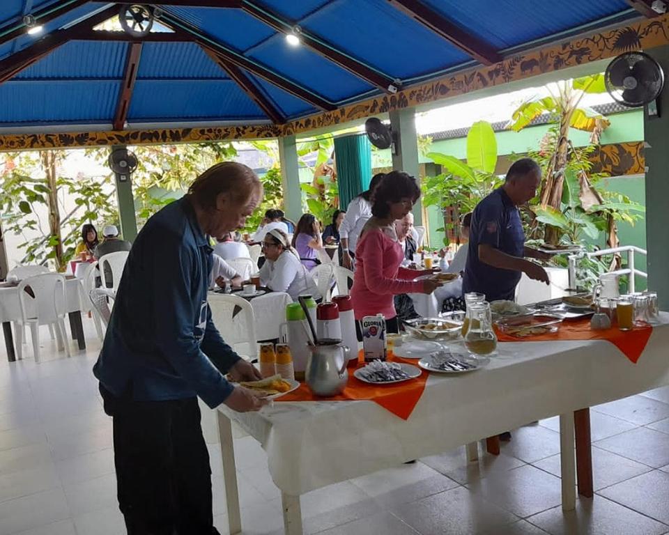 un grupo de personas sentadas en una mesa comiendo comida en Wikungo Hotel, en Puerto Nariño