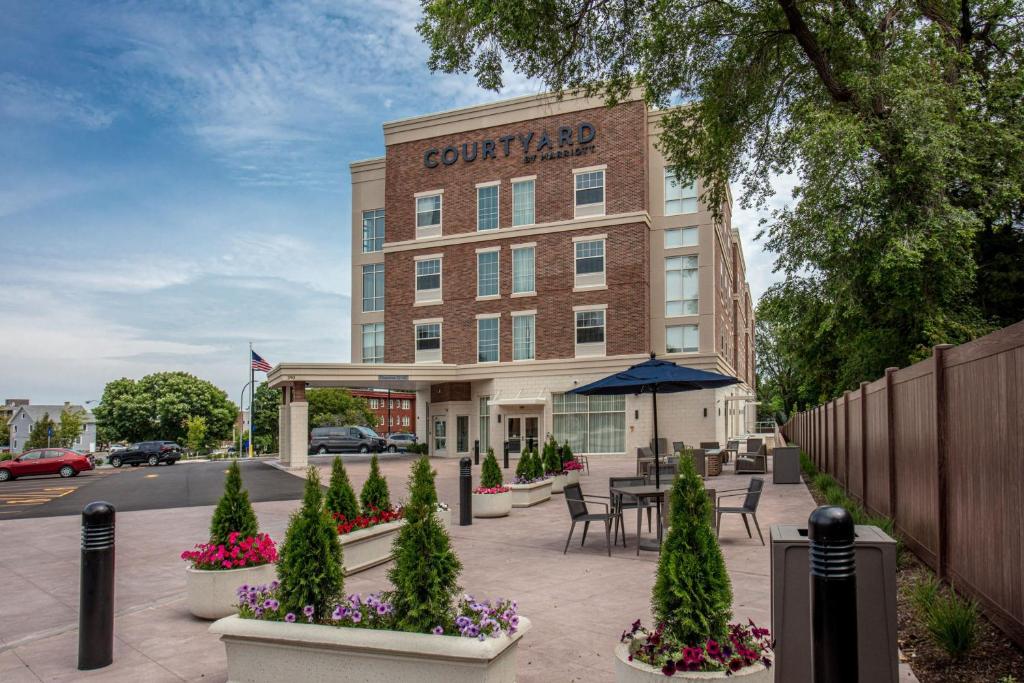 a court yard hotel with tables and chairs and flowers at Courtyard Rochester Downtown in Rochester