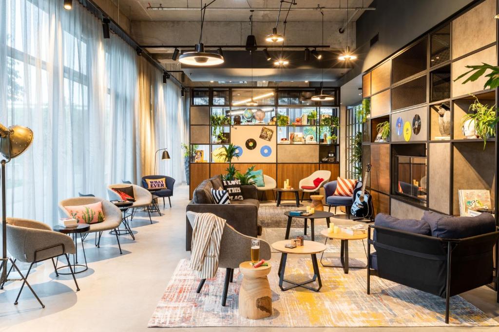 - un hall avec des canapés, des chaises et des tables dans l'établissement Moxy Berlin Airport, à Schönefeld