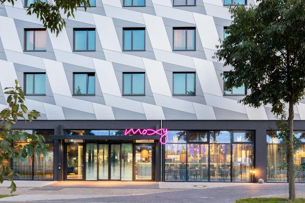 a facade of a building with a pink sign on it at Moxy Berlin Airport in Schönefeld