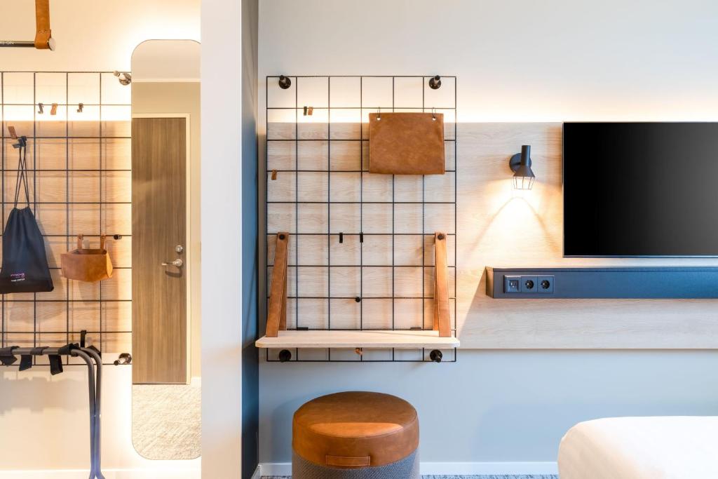 a living room with a tv and a stool at Moxy Berlin Airport in Schönefeld