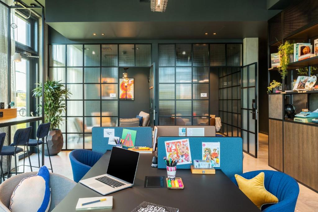 an office with a table with a laptop and chairs at Moxy Berlin Airport in Schönefeld