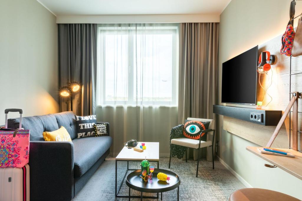 a living room with a couch and a tv at Moxy Berlin Airport in Schönefeld