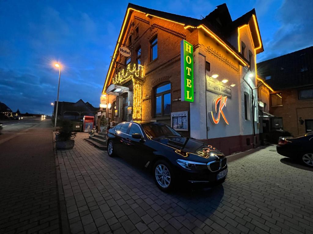 ein Auto, das vor einem Gebäude mit Neonschild parkt in der Unterkunft Krügers Apartment in Barsinghausen