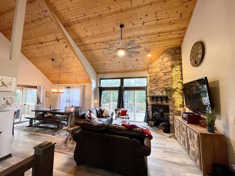 a living room with a couch and a stone fireplace at Gorgeous cabin 3bdrm/3bth, hot tub, fireplace, kid/pet friendly in Galena