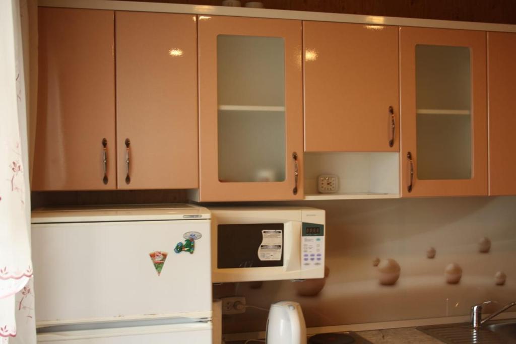 eine Küche mit Holzschränken und einem Kühlschrank in der Unterkunft Квартира на набережной in Pawlodar