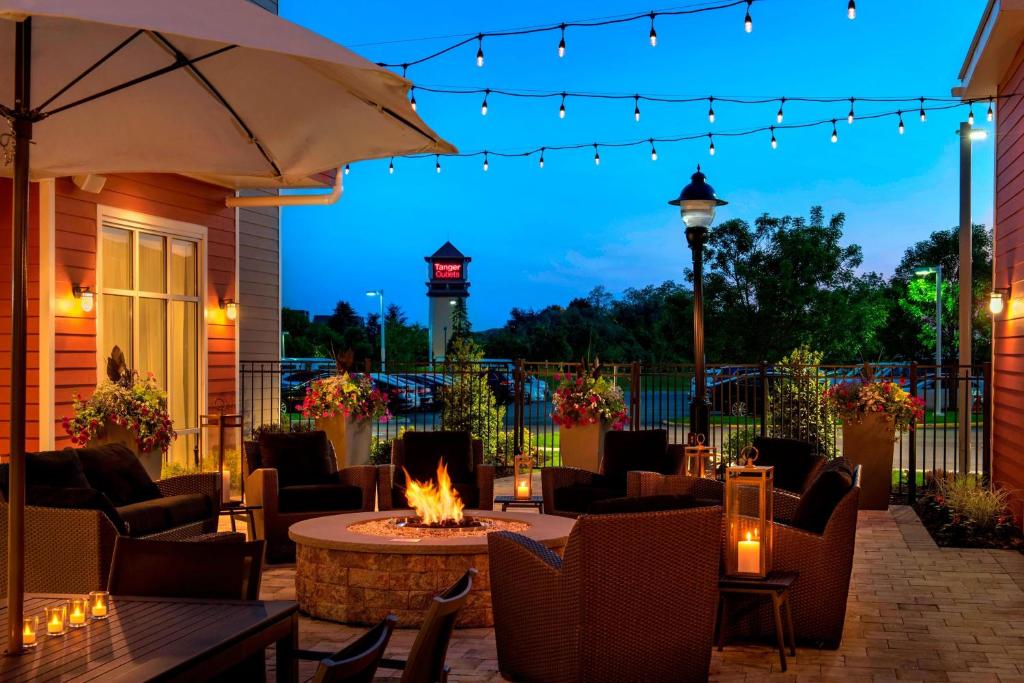 een patio met een vuurplaats, stoelen en verlichting bij Residence Inn by Marriott New York Long Island East End in Riverhead