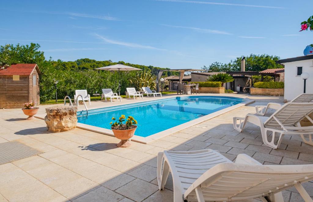 una piscina con sillas blancas y un patio en Villa Mariant con Piscina Privata, en Ruffano